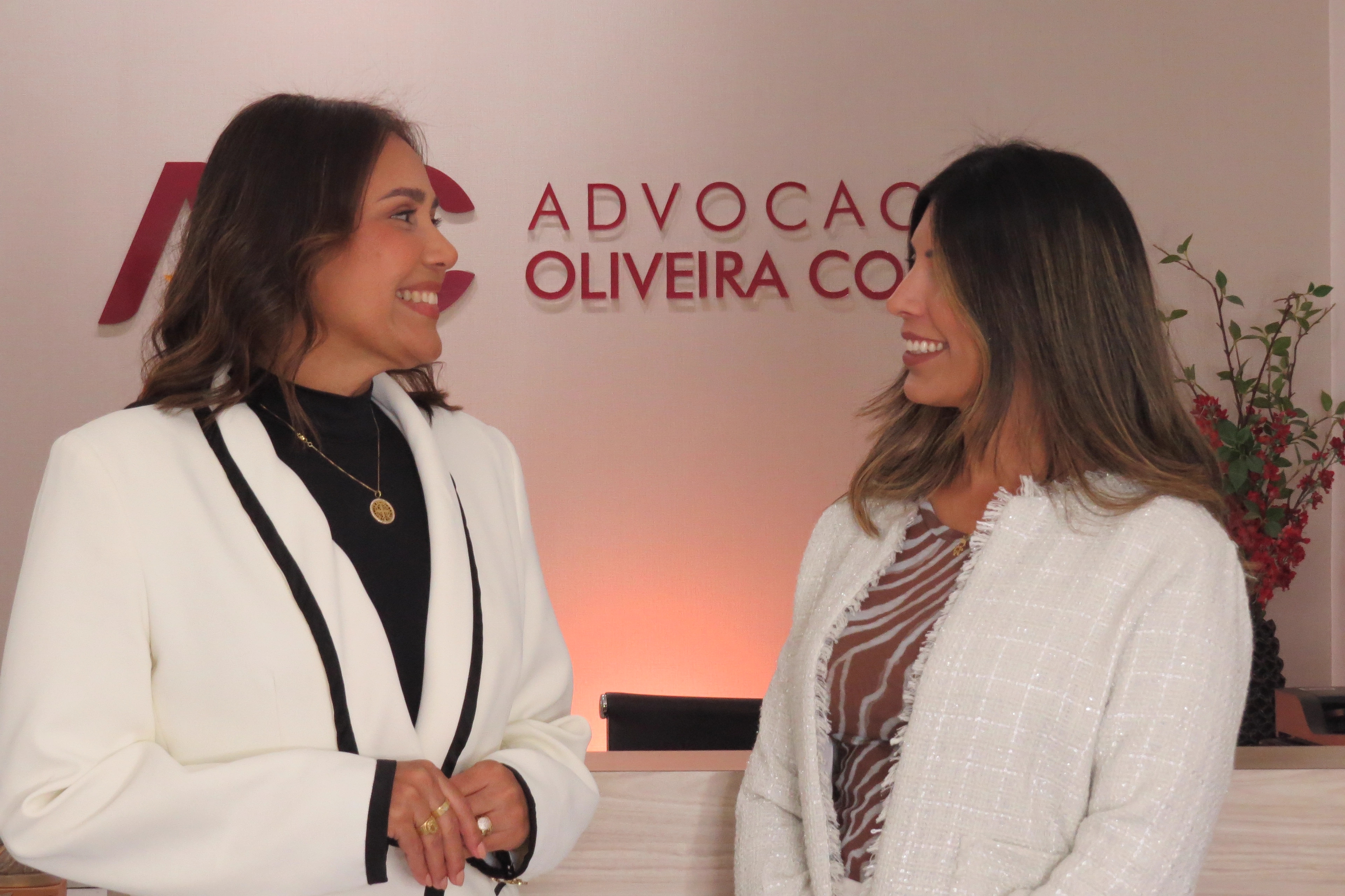 Duas advogadas do Advocacia Oliveira Costa conversando na recepção do escritório